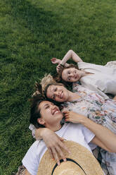 Glückliche junge Frau liegt mit Freunden im Park - OMIF00876