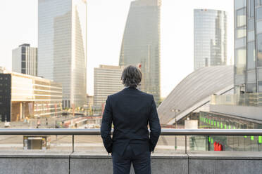 Businessman with hands in pockets standing in front of railing - OIPF02032