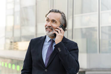 Smiling mature businessman with gray hair talking on smart phone - OIPF02034