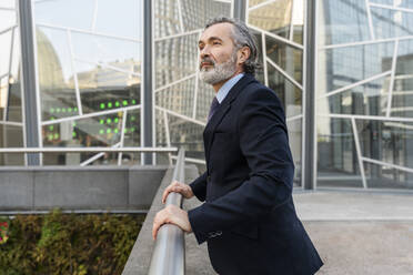 Mature businessman with gray hair standing by railing - OIPF02040
