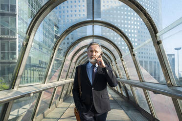 Mature businessman talking through smart phone on footbridge - OIPF02045