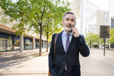 Smiling businessman with beard talking on smart phone - OIPF02059