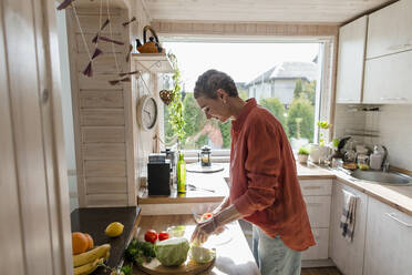 Woman preparing salad in kitchen at home - LLUF00564