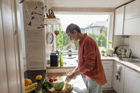 Frau bereitet Salat in der Küche zu Hause vor - LLUF00564