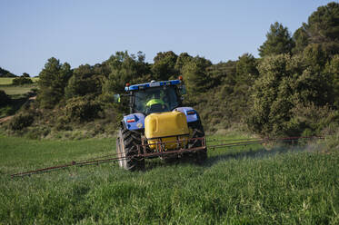 Junger Landwirt beim Sprühen von Dünger auf dem Feld - JCMF02262