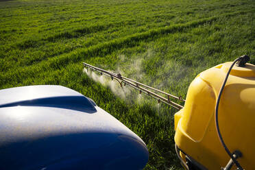 Pflanzenschutzspritze beim Sprühen von Dünger auf einem Feld an einem sonnigen Tag - JCMF02284