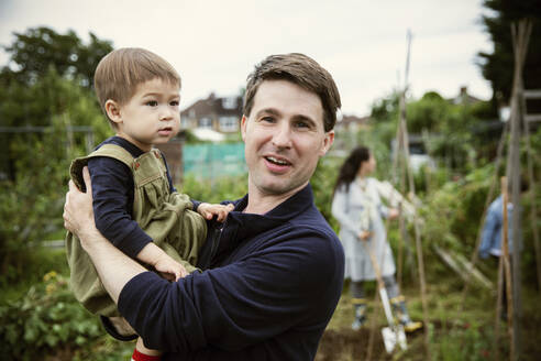 Portrait glücklicher Vater und kleiner Sohn im Garten - CAIF32749