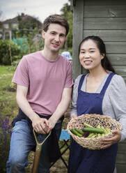 Portrait glückliches Paar bei der Ernte von frischem Gemüse im Garten - CAIF32759