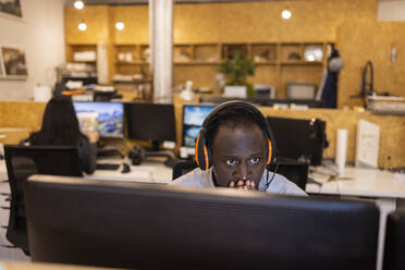 Konzentrierter Geschäftsmann mit Headset bei der Arbeit am Computer im Büro - CAIF32806