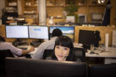Porträt einer lächelnden Geschäftsfrau mit Headset bei der Arbeit im Büro - CAIF32809