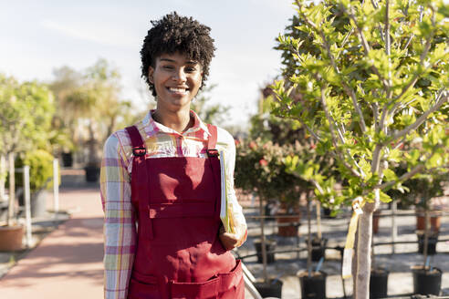 Confident owner with book standing by plant at nursery - JCCMF06400