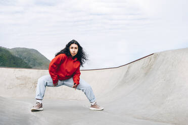 Frau mit schwarzen Haaren tanzt im Skateboardpark - OMIF00884