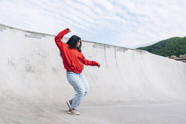 Frau mit erhobener Hand tanzt im Skateboardpark - OMIF00885