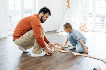 Vater mit Sohn baut zu Hause eine Spielzeugeisenbahnstrecke - VPIF06252