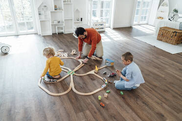 Father and son playing with toy train set at home - VPIF06261