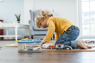 Blond boy playing with toy train set at home - VPIF06268