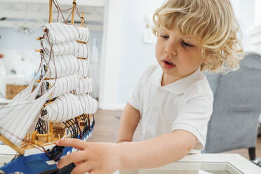 Süßer Junge spielt mit Spielzeugboot zu Hause - VPIF06275
