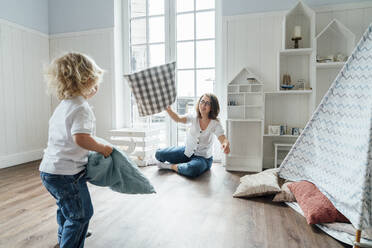 Happy mother and son playing with cushions at home - VPIF06289
