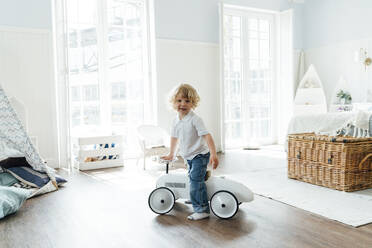 Lächelnder Junge mit Spielzeugauto beim Spielen zu Hause - VPIF06296