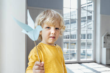 Niedlicher Junge mit Origami-Vogel zu Hause stehend - VPIF06323