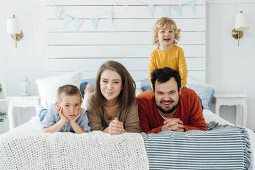 Glückliche Familie, die gemeinsam zu Hause auf dem Bett liegt - VPIF06329