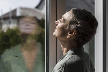 Ältere Frau mit kurzen grauen Haaren am Fenster - LLUF00608