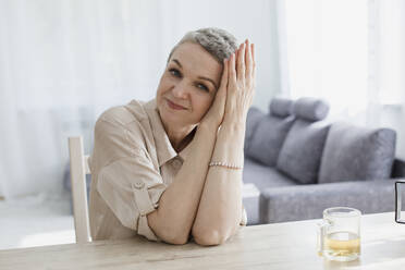 Portrait of mature woman sitting at table at home - LLUF00654