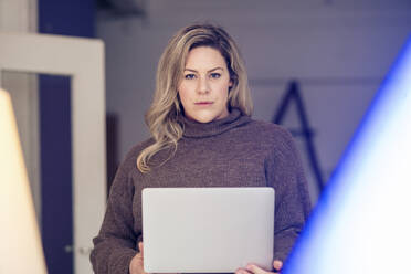 Selbstbewusste Geschäftsfrau mit Laptop am Arbeitsplatz - JOSEF10269