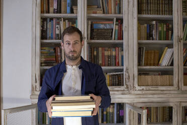 Mann mit Buch vor einem Bücherregal - VEGF05659