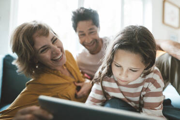 Happy parents looking at daughter using tablet PC - JOSEF10365