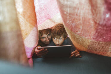 Happy mother and son with tablet PC under blanket at home - JOSEF10371