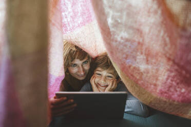 Happy mother and son using tablet PC under blanket - JOSEF10372