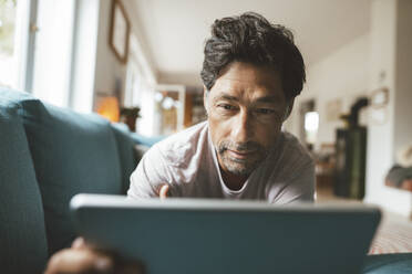 Älterer Mann mit Tablet-PC auf dem Sofa zu Hause - JOSEF10374