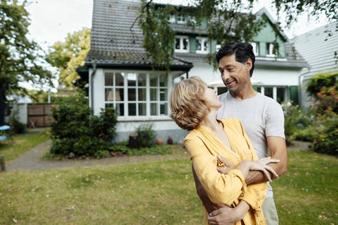 Glücklicher Mann und Frau stehen vor einem Haus - JOSEF10386