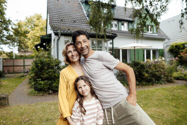 Happy parents with daughter standing in front of house - JOSEF10388