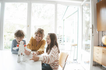 Glückliche Familie spielt zusammen mit Spielzeugroboter am Tisch sitzend - JOSEF10426