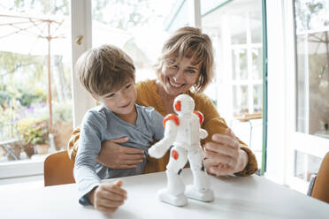 Happy mother and son playing with toy robot at home - JOSEF10427