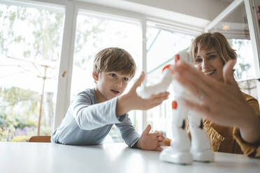 Mother and son playing with toy robot at home - JOSEF10428