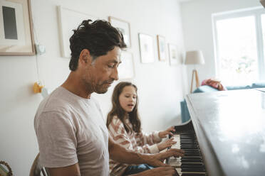 Father and daughter playing piano together at home - JOSEF10431