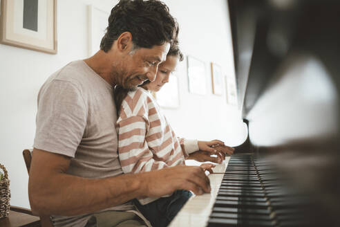 Glücklicher Vater unterrichtet seine Tochter zu Hause am Klavier - JOSEF10432