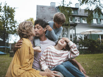 Couple kissing each other by playful son and daughter in back yard - JOSEF10445