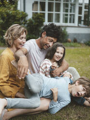 Playful boy with family enjoying in back yard - JOSEF10499