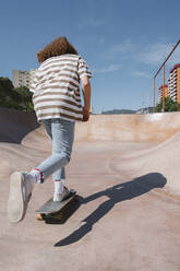 Junger Mann beim Skateboarden auf einer Sportrampe an einem sonnigen Tag - MMPF00087