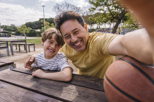 Cheerful man with son taking selfie on sunny day - MMPF00121