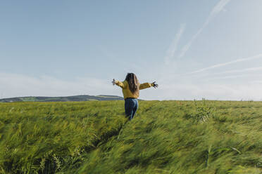 Young woman standing with arms outstretched in meadow - DMGF00738