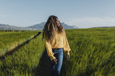 Young woman walking in meadow on sunny day - DMGF00742