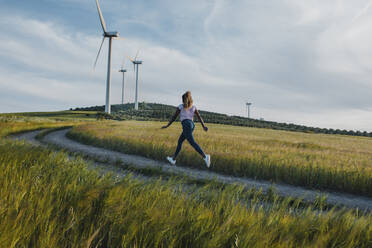 Young woman running on footpath amidst meadow - DMGF00756