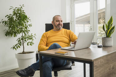 Mature businessman on video call through laptop at office - OSF00001