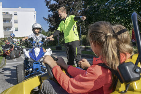 Junger Ausbilder hilft einem Jungen beim Quadfahren in der Verkehrserziehung - RNF01376