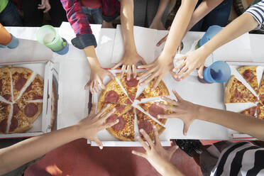 Hands of children reachuing for pizza on table - RNF01381